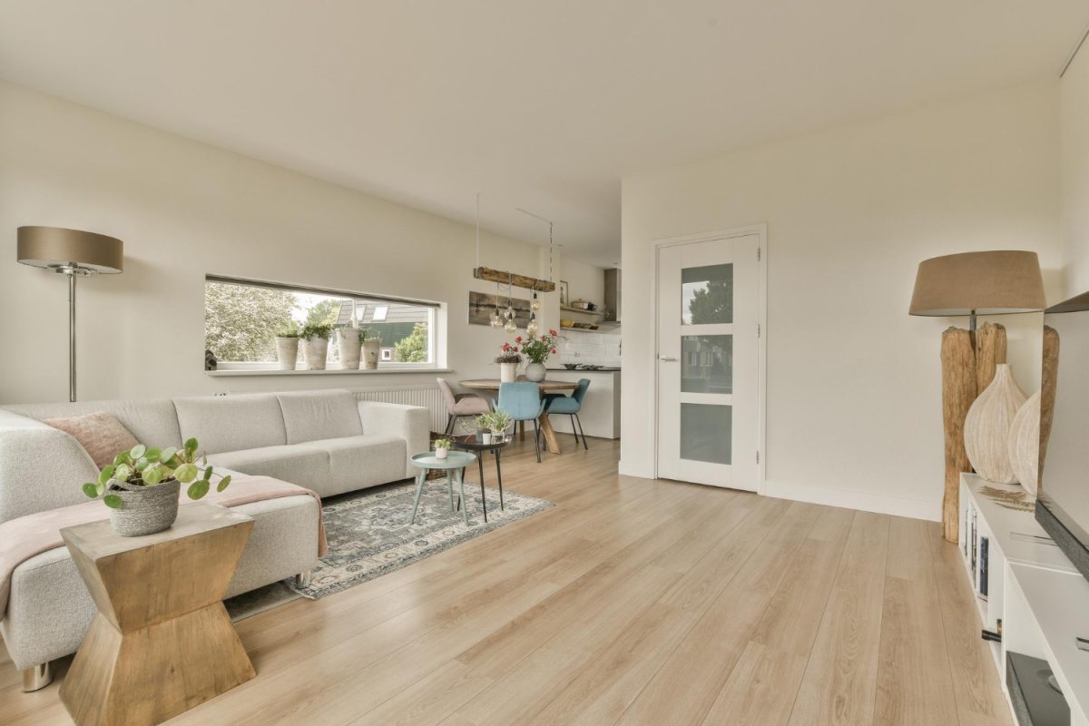 Un salon avec des murs blancs et un sol en bois au centre de la pièce est une zone de cuisine ouverte